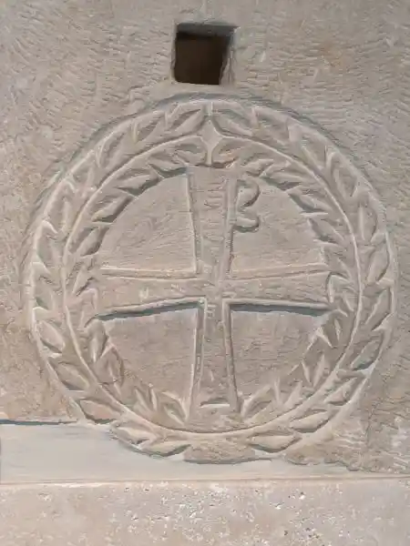 Close-up of a limestone funerary stele fragment with a relief cross in a wreath